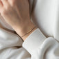Armband LANA in Gelbgold getragen an Handgelenk von Person in weißem Pullover