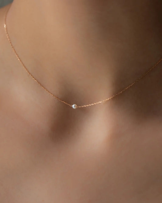Nahaufnahme von Halskette SEA MINI in Roségold mit weißer kleiner Perle getragen an Hals von Frau