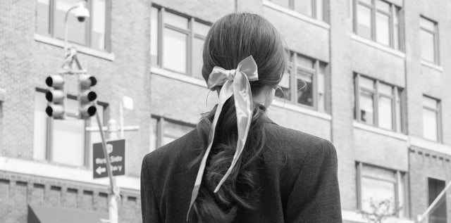 gehende Frau mit gebundenen Seidentuch im Haar und schwarzem Blazer in New York City