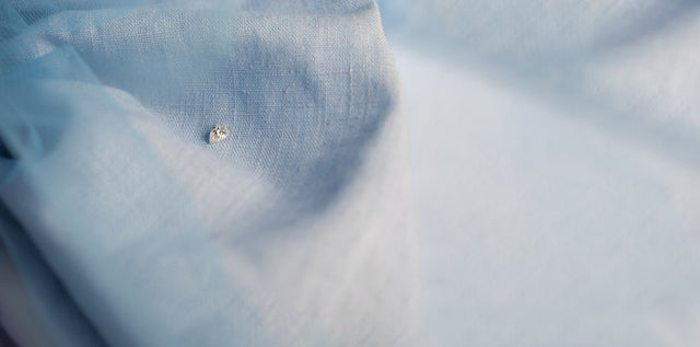 einzelner weißer Diamant in pear cut auf blauem Stoff