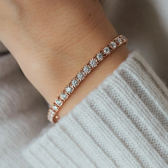Nahaufnahme von Armband FERNANDA in Roségold mit weißen Diamanten auf Arm von Frau in Strickpullover