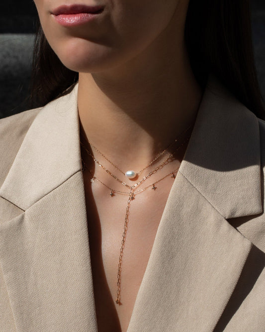 Frau in beigem Blazer mit Halsketten Layering mit Halskette Hanna, Halskette Anna Signature Star 7 und Halskette Lenox Eve in Roségold mit ovaler Perle