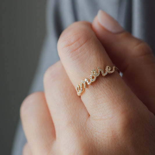 Gelbgoldener Ring an Finger mit Aufschrift Amore und weißen Diamanten