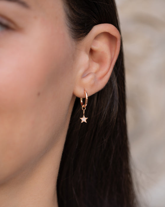 Anhänger Alice in 18 KT Rosegold mit einem Stern-Anhänger besetzt mit weißen Diamanten getragen an einer Kreole am Ohr