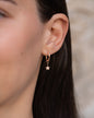Anhänger Alice in 18 KT Rosegold mit einem Stern-Anhänger besetzt mit weißen Diamanten getragen an einer Kreole am Ohr