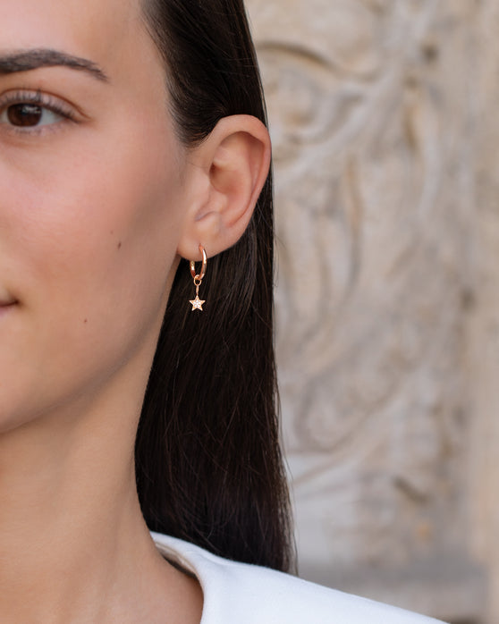 Anhänger Alice in 18 KT Rosegold mit einem Stern-Anhänger besetzt mit weißen Diamanten getragen an einer Kreole am Ohr