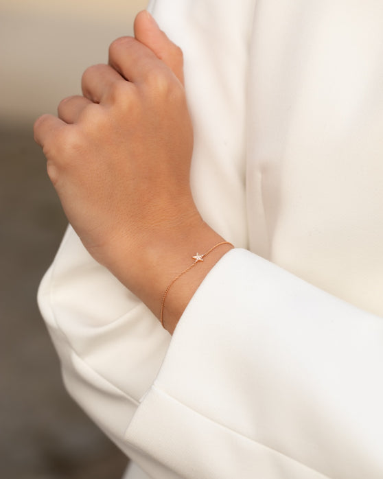 Filigrane Armkette in 18 KT Rosegold mit Anhaenger in Sternenform mit weißen Diamanten getragen an Handgelenk