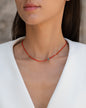 Kurze, rote Halskette mit Edelsteinen aus 18 KT Roségold. Halskette mit Karneolen und Türkisen – ein sommerliches Schmuckstück von ANNA. Getragen am Hals einer Frau mit schwarzen Haaren und weißem Blazer.
