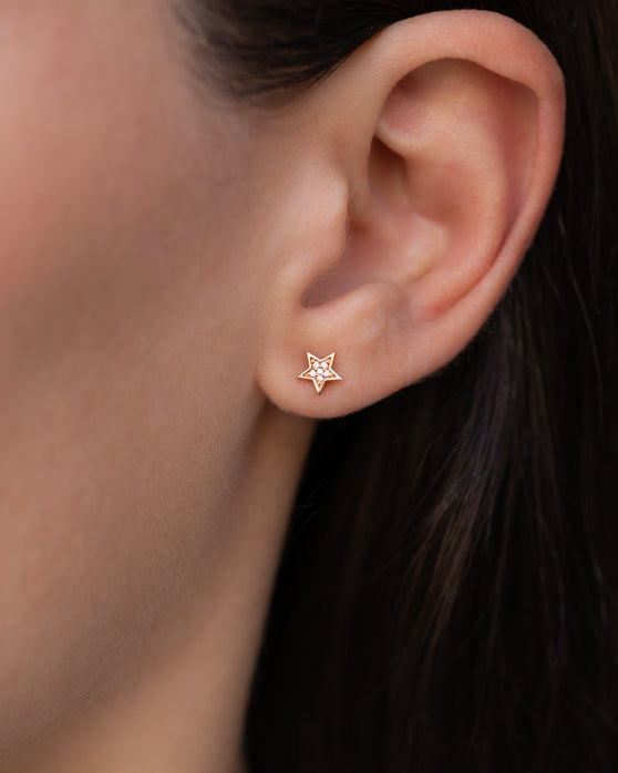 Kleiner Ohrstecker in 18 KT Rosegold mit einem Stern besetzt mit weißen Diamanten, getragen an einem Ohr