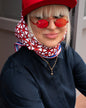 Rotes Seidentuch mit blau-weißem Muster als stilvolles Accessoire am Kopf getragen von einer blonden Frau.