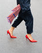 Rotes Seidentuch mit blau-weißem Muster als stilvolles Accessoire an der Hose getragen von einer Frau mit roten Schuhen und dunkelblauem Jumpsuit.