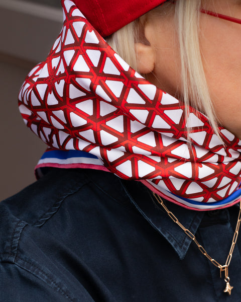 Rotes Seidentuch mit blau-weißem Muster als stilvolles Accessoire am Kopf getragen von einer blonden Frau.