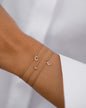 Drei personalisierte Armbänder aus 18 KT Roségold von ANNA mit Initialen und Buchstaben-Anhänger mit Diamanten. Individueller Schmuck zum Kombinieren für Dein Armcandy. Getragen am Handgelenk von einer Frau mit weißer Bluse.