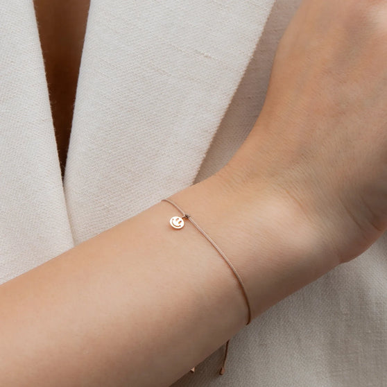 Tragefoto von 18 KT Roségold Smileyanhänger auf beigen Stoffarmband 