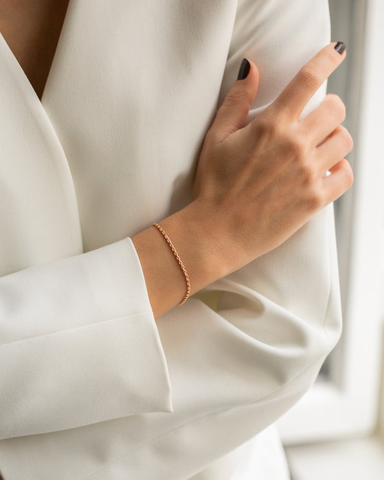 Eine schlichte Armkette aus Roségold ohne Anhaenger. Feine Gliederkette, die nicht zu grob ist und nicht zu zart. Getragen an einem Frauenhandgelenk.