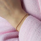 Nahaufnahme von Armkette Lana in Rosegold getragen an Handgelenk von Frau in Rosa Weste