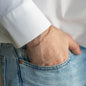 Armgelenk von Mann in weißem Hemd und Jeans mit zarter Glieder Armkette in 18 KT Roségold