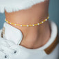 Fußband MALIBU in Sonnengelb mit weißen Perlen getragen an Fußgelenk