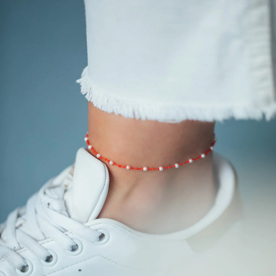 Fußband MALIBU in Leuchtendem Rot mit weißen Perlen getragen an Fußgelenk