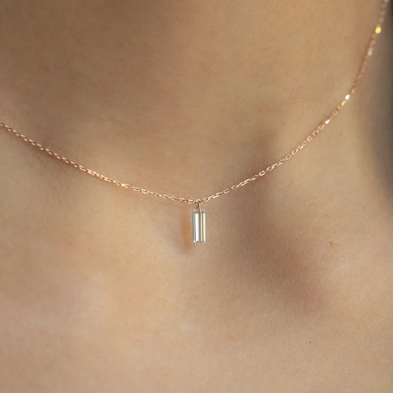 Nahaufnahme von ANNA Halskette Paulina in 18 KT Roségold mit weißem Diamanten im Baguette Schliff, getragen um Hals