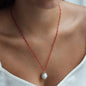 Nahaufnahme von Stoffhalskette Halskette Rio in Rot mit Perlenanhänger getragen von Frau