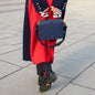 Handtasche ELLEN in Mitternachtsblau getragen von Frau in dunkleblauem Mantel kombiniert mit roten Details
