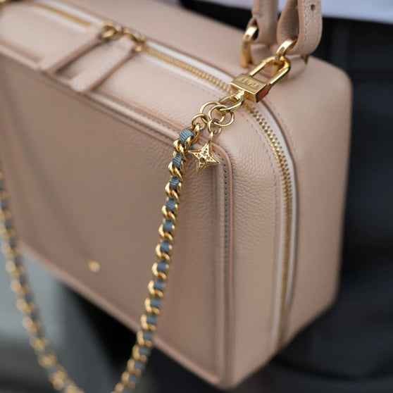 Nahaufnahme von ANNA Schlüsselkette MAX in Gold mit grauem Stoffband getragen an Handtasche ELLEN