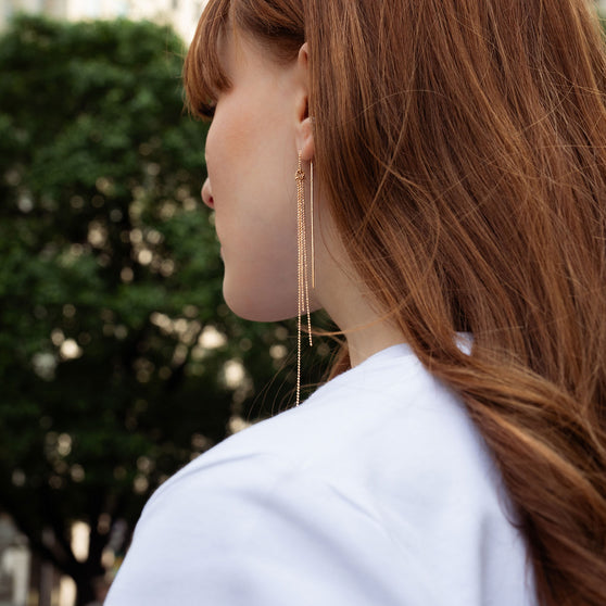 Frau mit langen roten Haaren mit langem Kettenohrring Ohrring Bisou in 18 KT Roségold