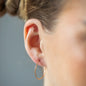 Ear Piercing Cross in Kreuzform, mit weißen Diamanten und in 18 KT Rosegold getragen an Ohr von Frau