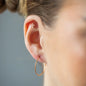 Nahaufnahme Ear Piercing Cross in Kreuzform, mit weißen Diamanten und in 18 KT Rosegold getragen an Ohr von Frau