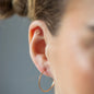 Ear Piercing PEACE mit Peace-Zeichen, weißen Diamanten und in 18 KT Rosegold getragen an Ohr von Frau