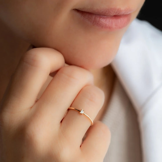 Nahaufnahme von zartem 18 KT Roségold Ring mit weißem Diamanten an Ringfinger von Frau