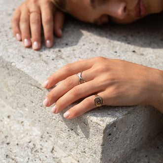 Ring Xenia in Sterling Silber getragen von liegender Frau auf Betonboden
