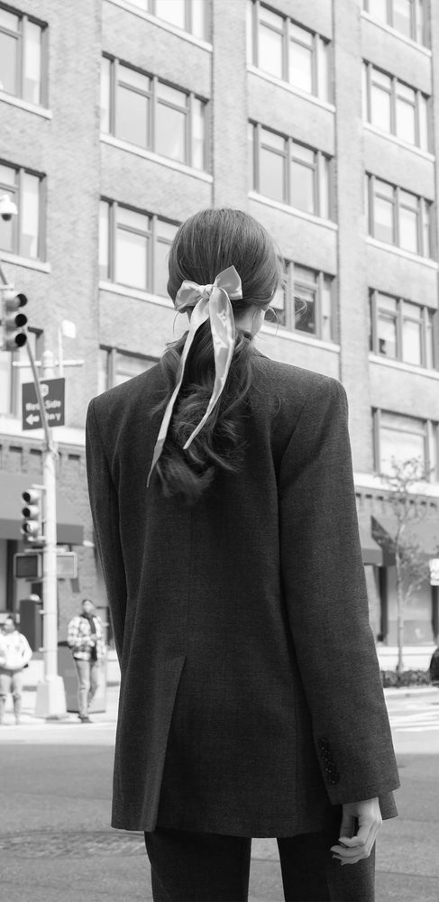 gehende Frau mit gebundenen Seidentuch im Haar und schwarzem Blazer in New York City