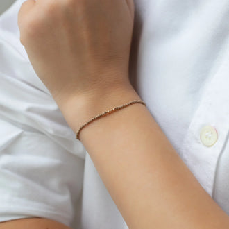 Armband KAI mit beigem Stoffband und drei Perlen aus 18 KT Roségold getragen an Handgelenk