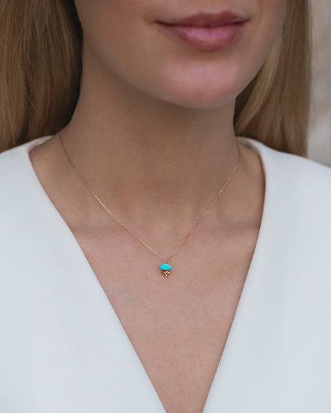 Zarte, kurze Halskette aus 18 KT Roségold mit einem Tuerkis-Anhaenger, getragen am Hals von einer blonden Frau mit weissem Blazer.