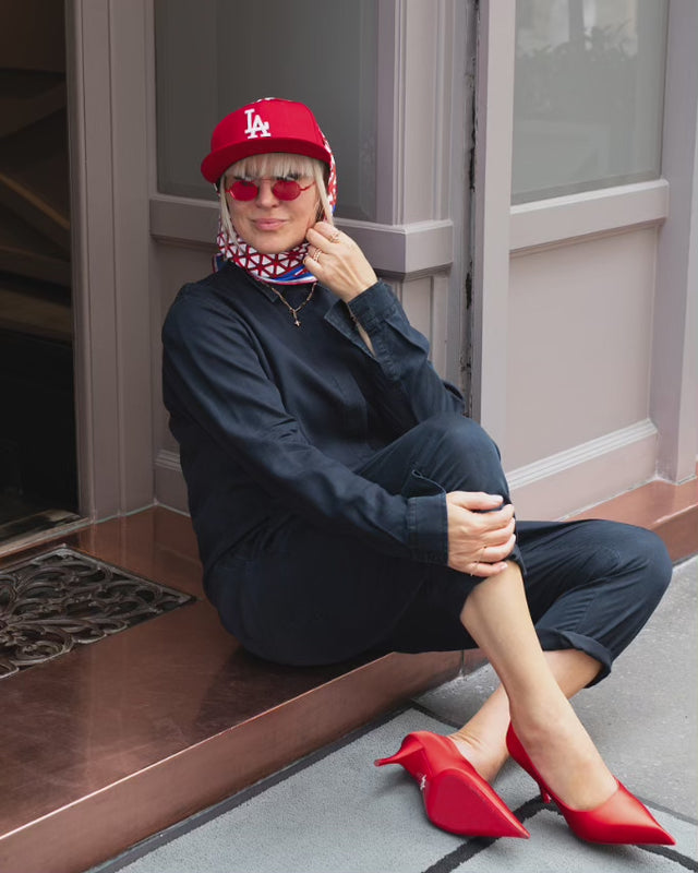 Rotes Seidentuch mit blau-weißem Muster als stilvolles Accessoire am Kopf getragen von einer blonden Frau.