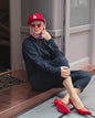 Rotes Seidentuch mit blau-weißem Muster als stilvolles Accessoire am Kopf getragen von einer blonden Frau.