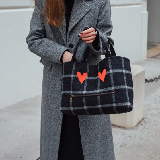 Handtasche MONDAY HEART schwarz kariert getragen von Frau in grauem Wintermantel