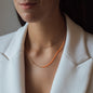 Halskette NALA mit orangenen Details in Roségold getragen von Frau in weißem Blazer