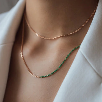 Close up von Halskette NALA mit Grünen Details in Roségold getragen von Frau in weißem Blazer