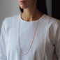 lange Halskette NALA mit orangenen Details in Roségold getragen von Frau in weißem Shirt