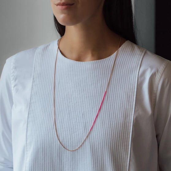 lange Halskette NALA mit pinken Details in Roségold getragen von Frau in weißem Shirt