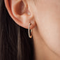 Close up von mit weißen Diamanten besetztem goldenem Ohrring in Ohr von Frau
