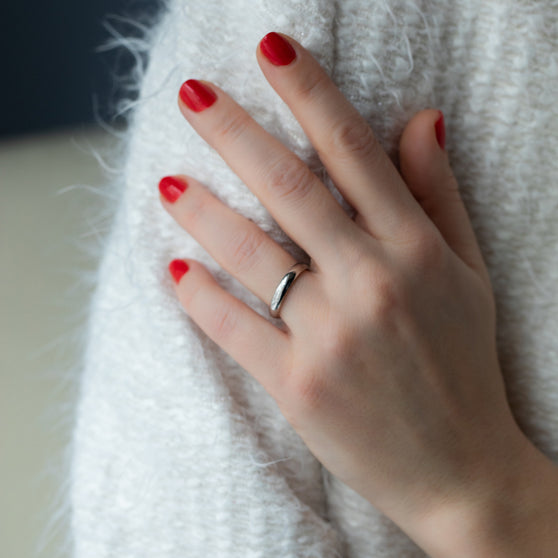 Frauenhand mit rot lackierten Fingernägel und weißgoldenem Ehering an Ringfinger