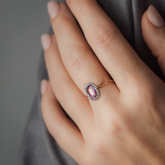 Close up von Frauenhand mit roségoldenem Ring mit großem Saphier und weißen Diamanten