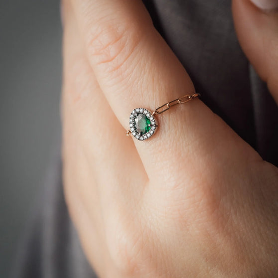 Detailaufnahme von Finger mit roségoldenem Ring mit grünem Tsavorit und mit weißen Diamanten besetzt aus Roségold