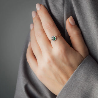 Frauen Hand an Oberarm abgestützt mit Roségoldenem Ring mit großem Tsavorit und weißen Diamanten