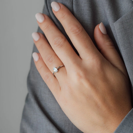 Hand mit weißem Diamantring auf Ringfinger
