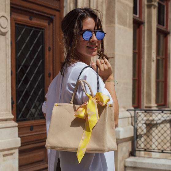 Seidentuch LOLA in Rosa-Gelb an Handtasche getragen von Frau mit Sonnenbrille